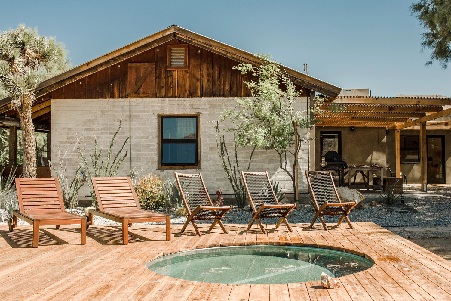 Patio deck with teak seating and a cowboy pool at Hey Cowboy vacation rental near Joshua Tree National Park, California.
