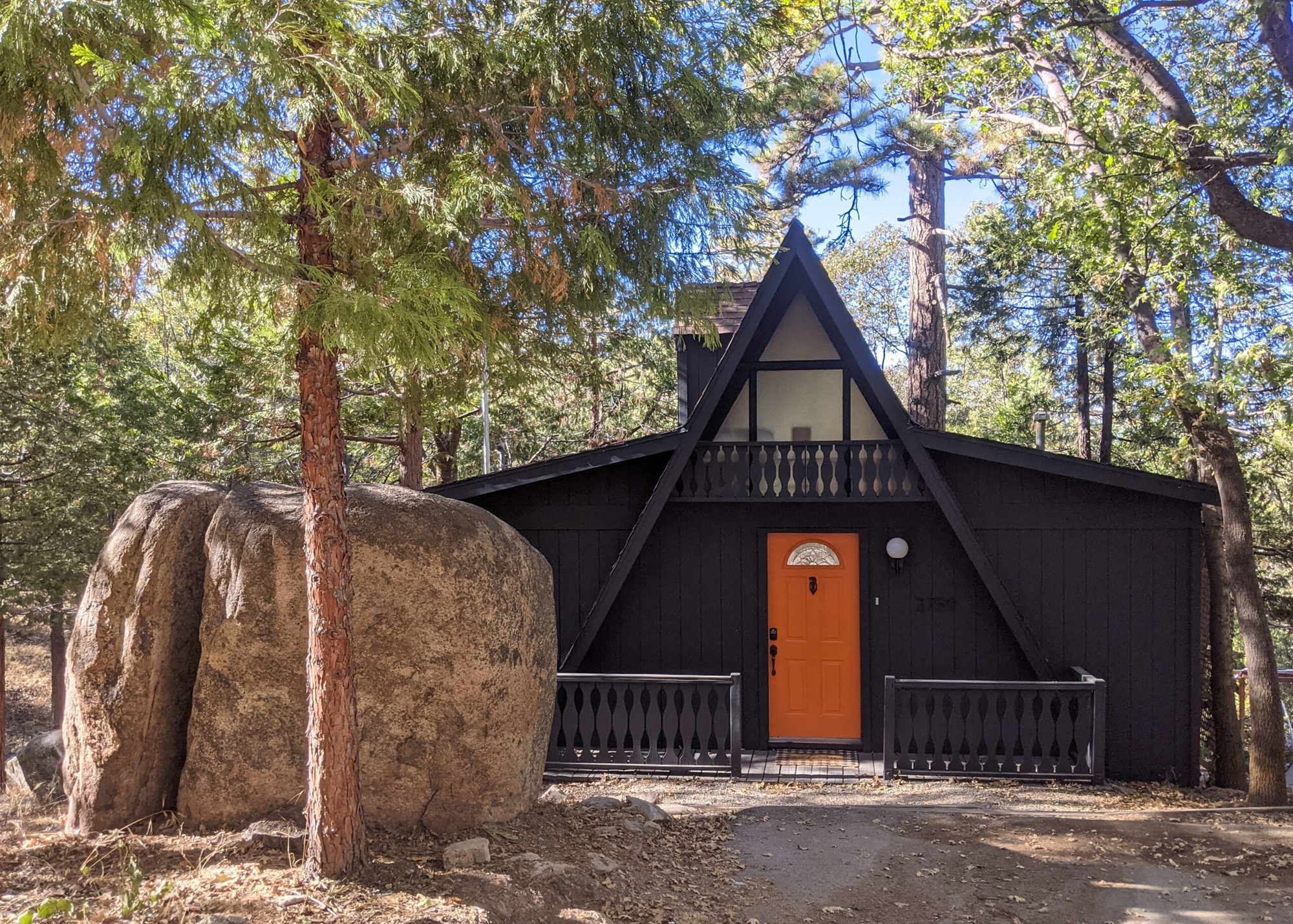 Exterior view of a brown A-frame cabin with an orange door called Hideout at Split Rock located in Lake Arrowhead, California.