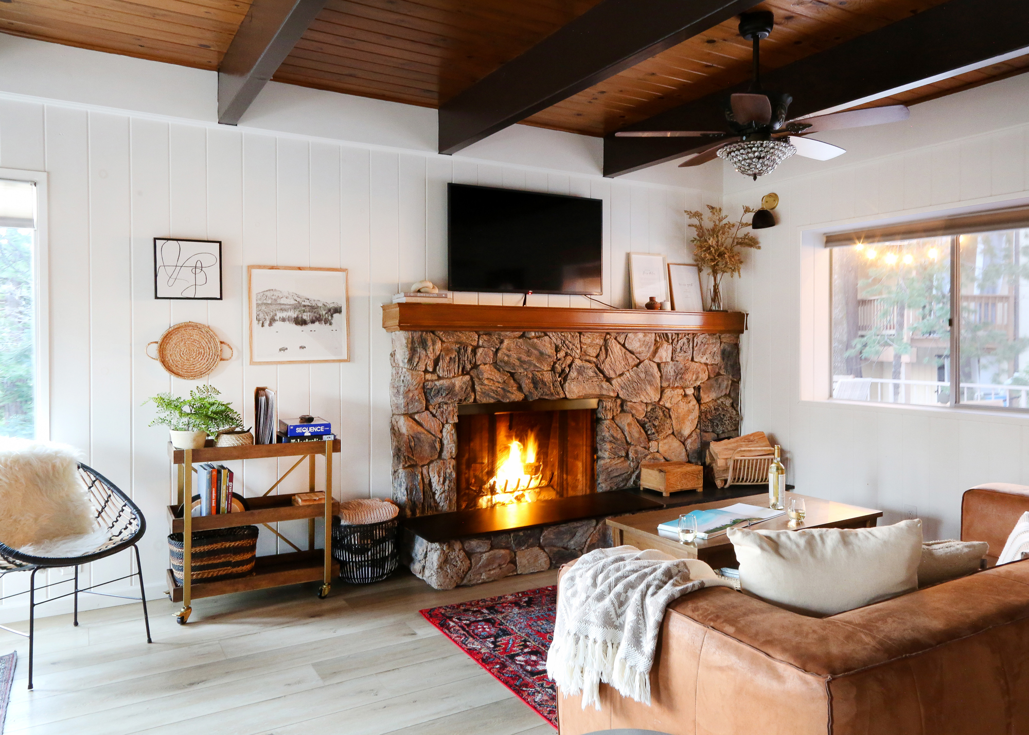 Interior view of a living room with large stone fireplace of Casa Cabina cabin rental in Lake Arrowhead, California.