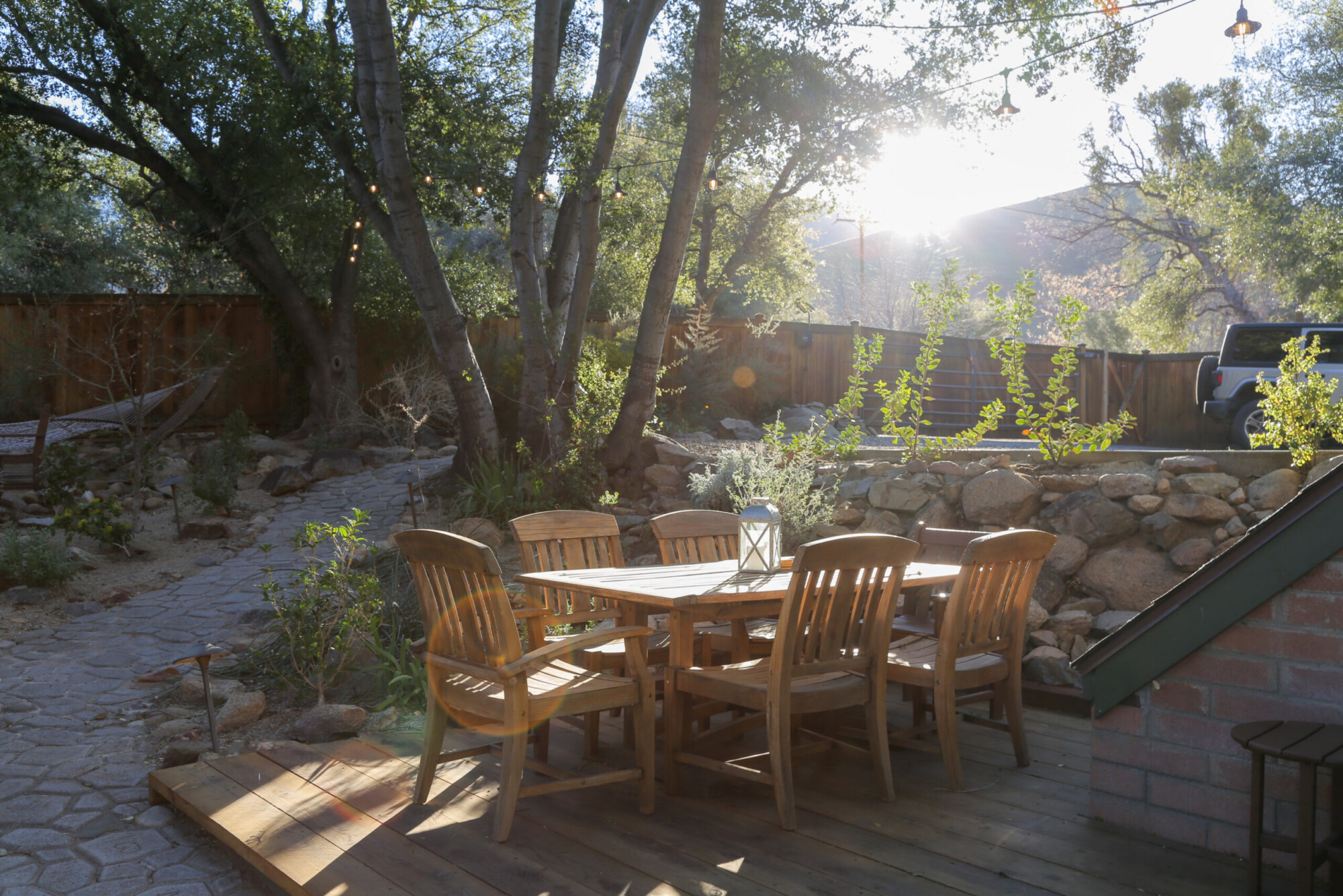View of a wood dining table for six on a wooden platform set among some trees at Kern River House's River Willow Cabin in Kernville, California.