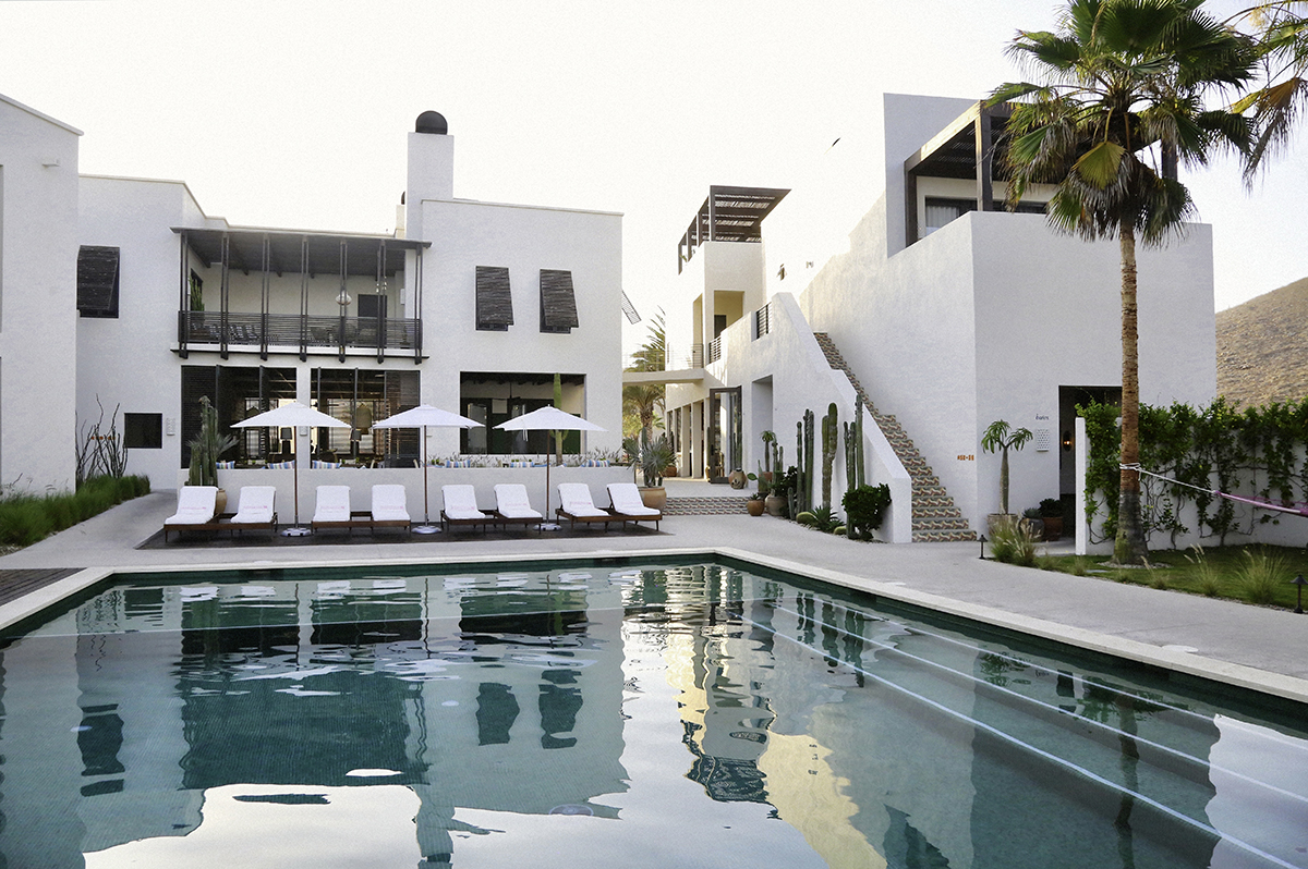 The pool with lounge seating and hotel in the background at Hotel San Cristóbal in Todos Santos, Baja California Sur, Mexico.