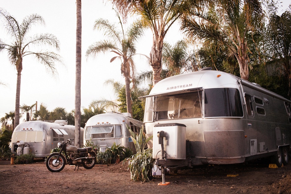 Three Airstream trailers set in some palms at Caravan Outpost in Ojai, California.