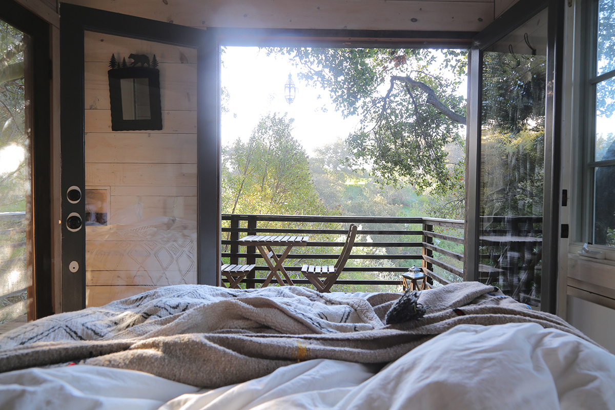 Looking out at the greenery through patio doors from the bed at Topanga Treehouse in California.