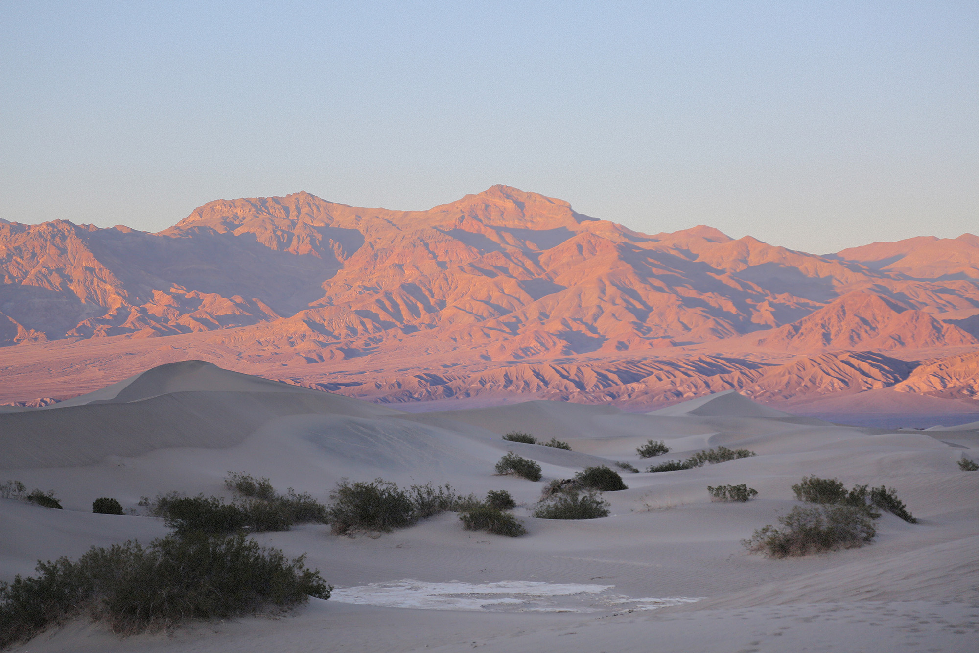Sunrise glow on the mountains viewed from the Mesquite Flat Sand Dunes in Death Valley National Park, California.