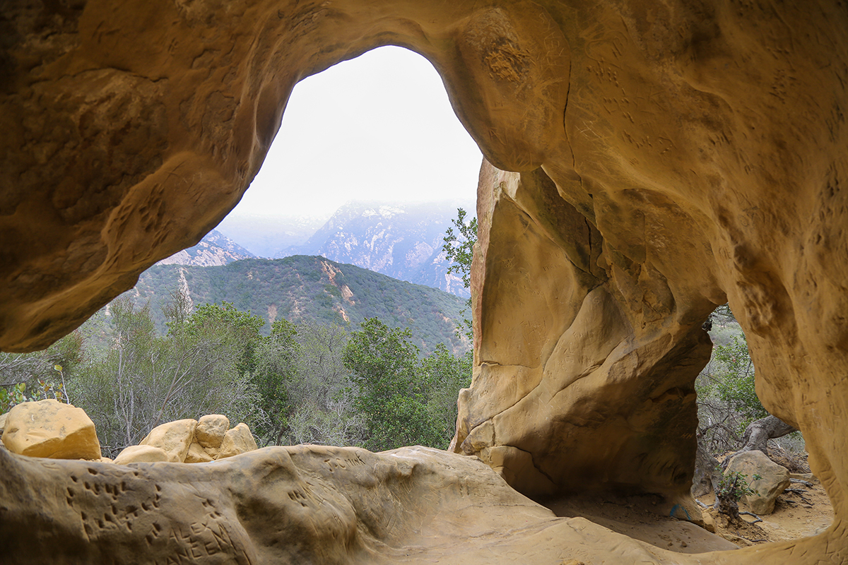 View of a hilly landscape with green vegetation through a cave at the Gaviota Wind Caves near Santa Barbara, California.