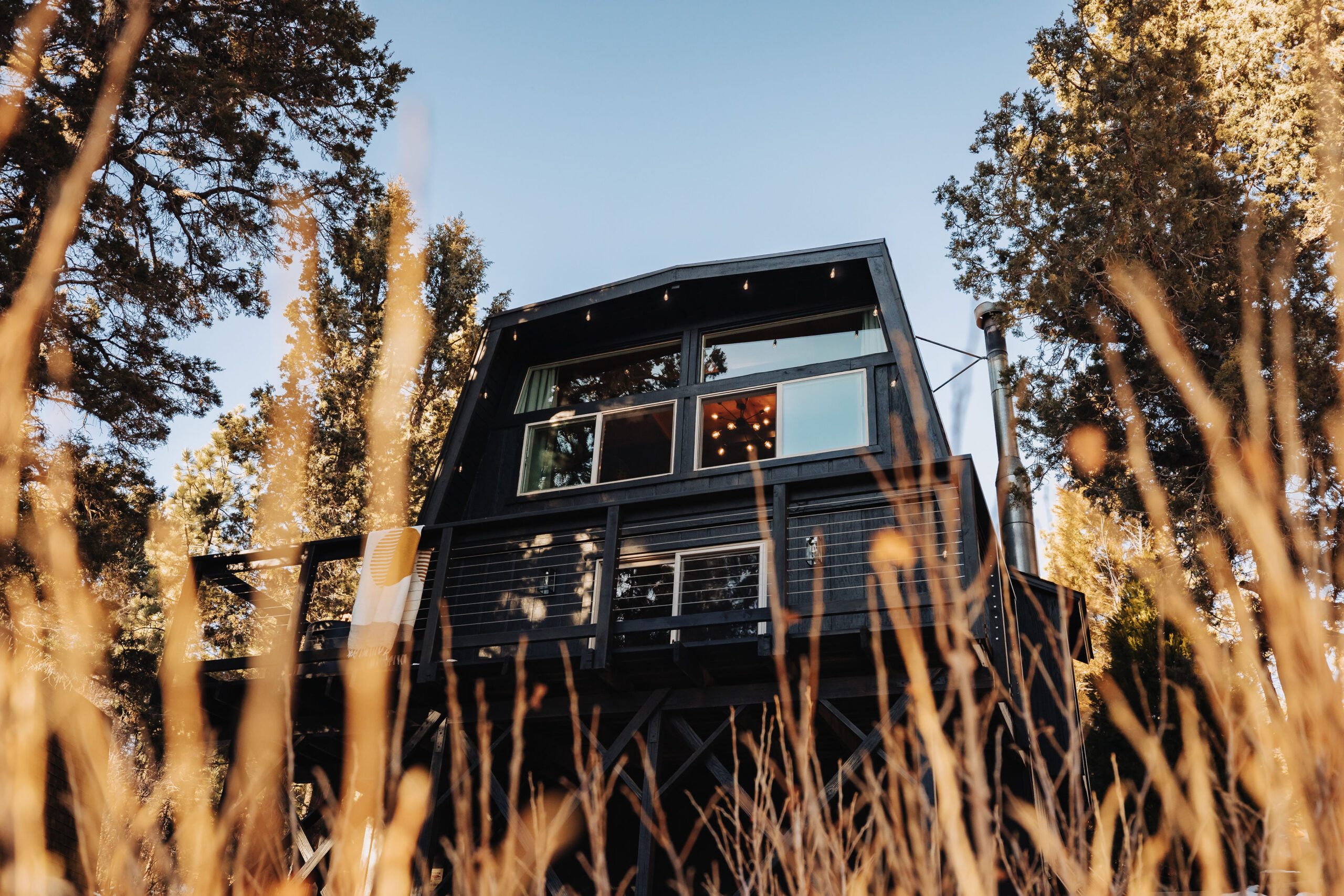 Exterior view of a black cabin and deck at Moondance Cabin vacation rental in Big Bear, California. Photo by Gianna Christina.