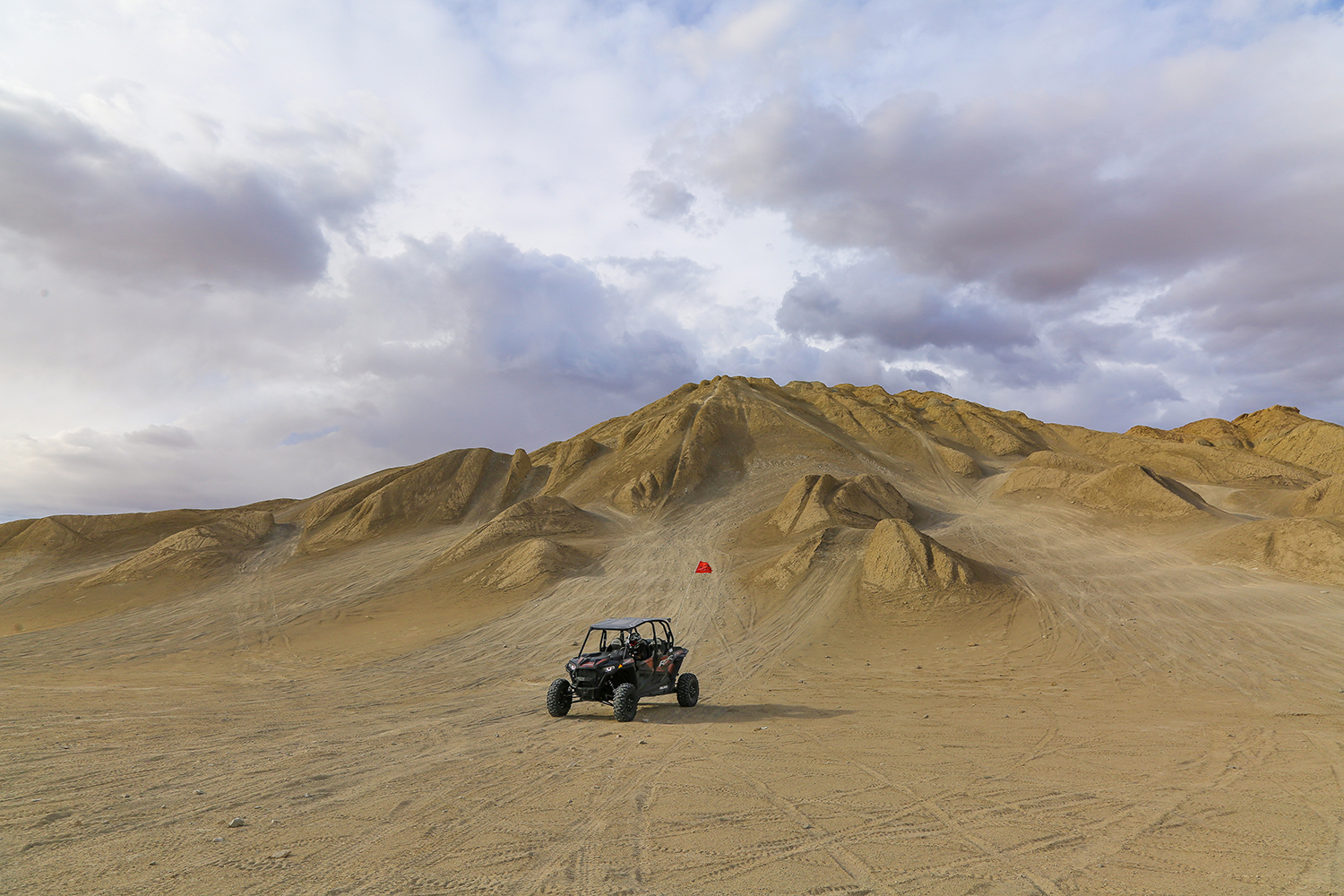 Photo of a black off-roading vehicle called an OHV buggy parked against a hilly desert terrain course near Borrego Springs, California.