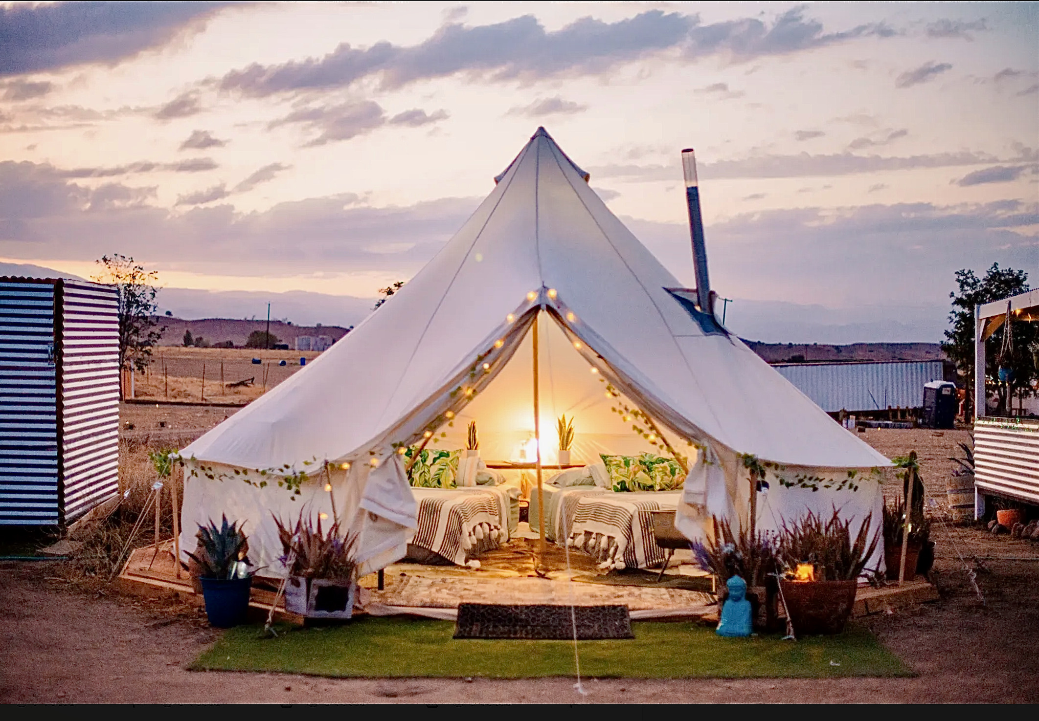 Exterior view of a white glamping tent set up in the desert landscape.