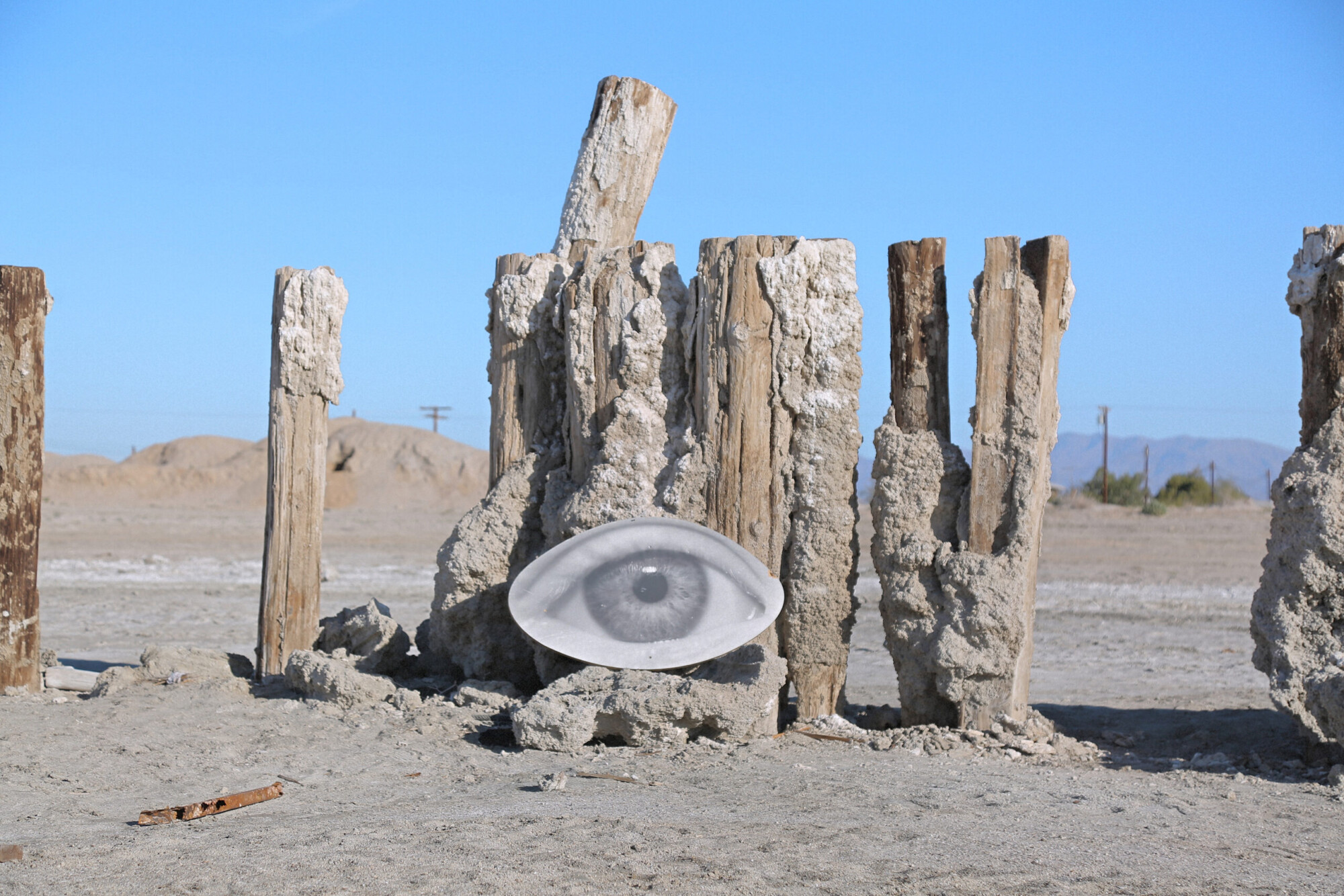 Outsider art of an image of an eye against a crumbling fence in Bombay Beach, California.