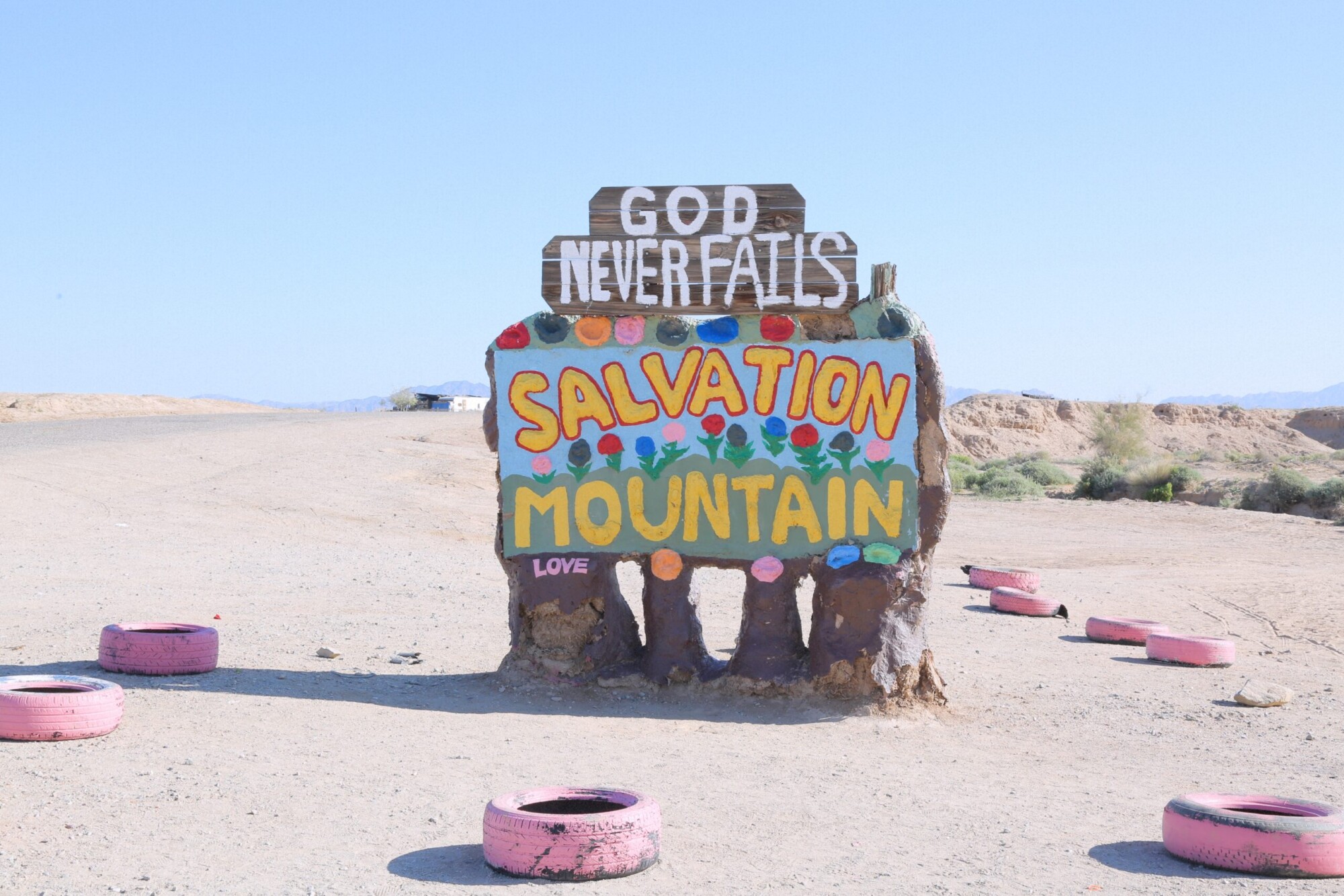 A hand painted sign at Salvation Mountain that reads 'God never fails. Salvation Mountian. Love'