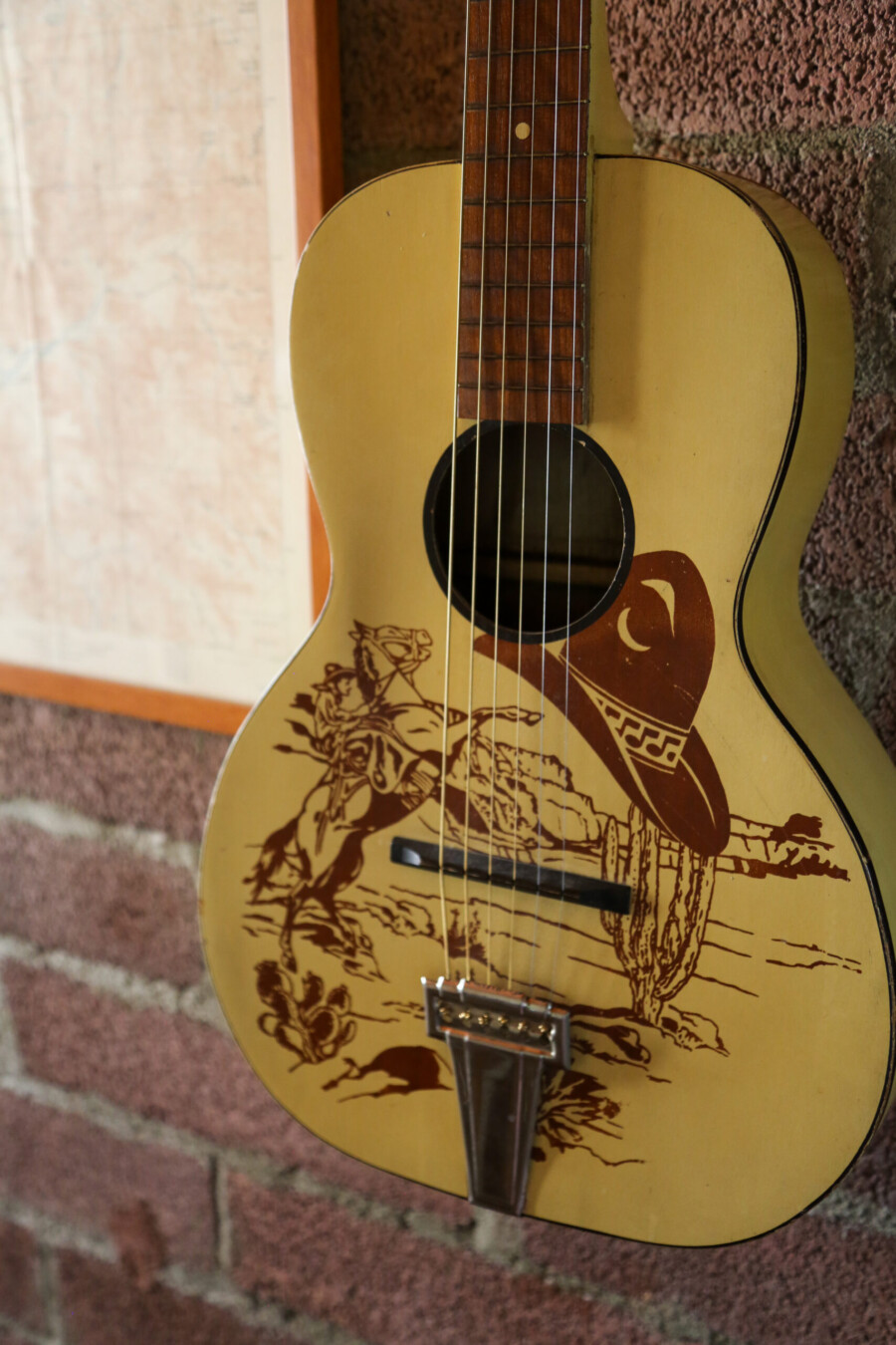 View of a guitar with cowboy art hanging in the dining nook of Kern River House's River Willow Cabin in Kernville, California.