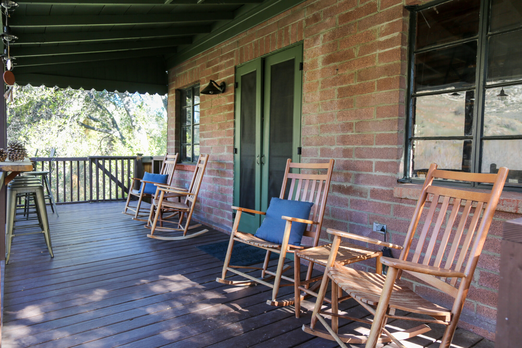 Outdoor porch with several rocking chairs and stools at Kern River House's River Willow Cabin in Kernville, California.