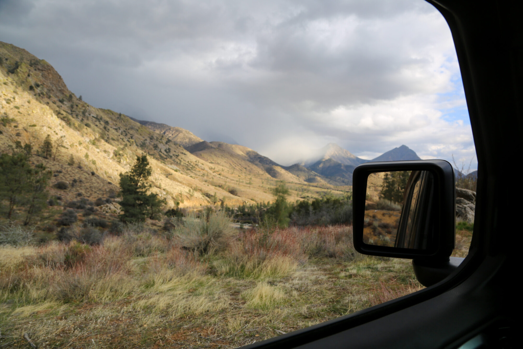 Photo through a vehicle window at an arid hilly landscape taken while off-roading near Kernville, California.