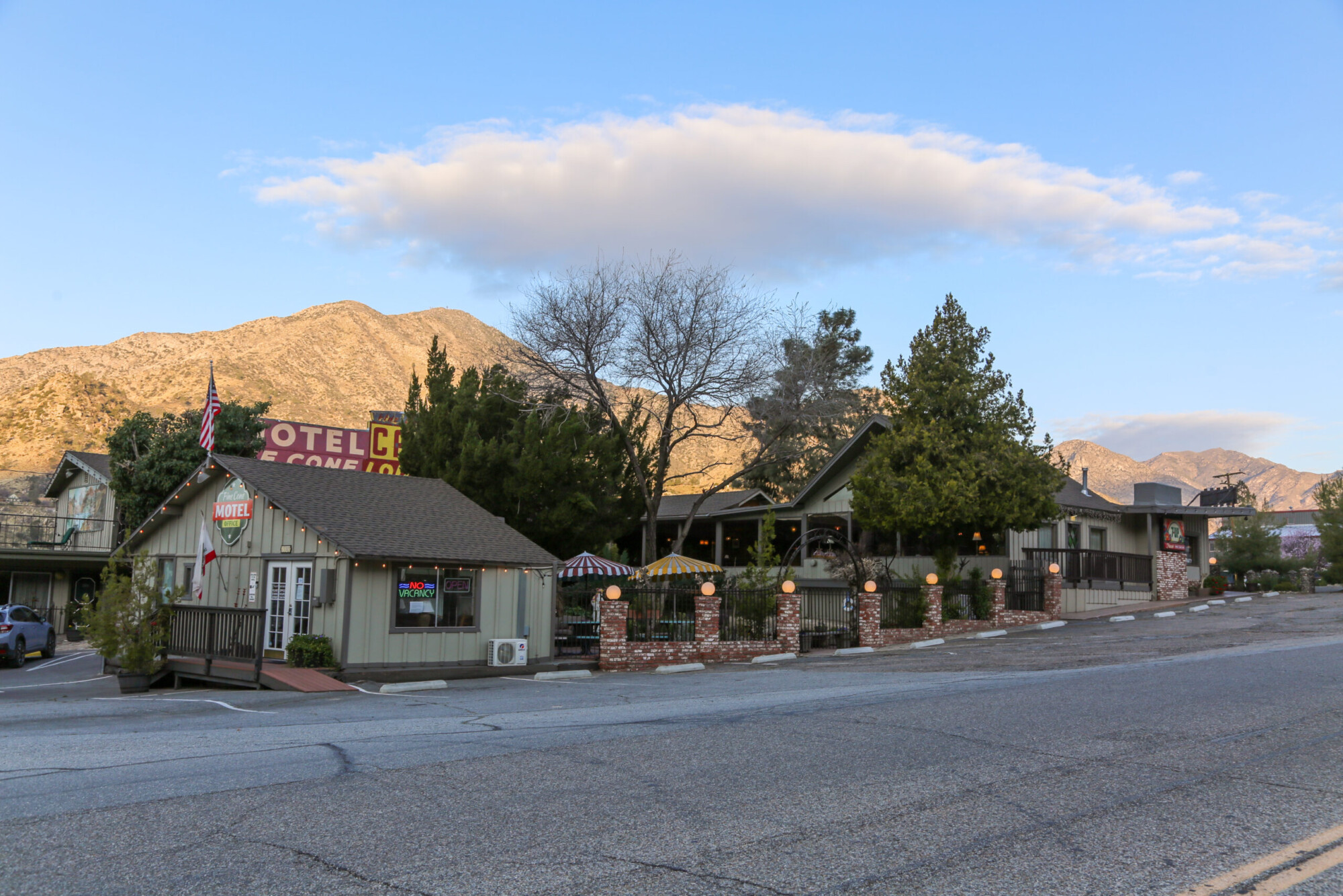 Exterior view of a small light green with brown trim motel called Piazza's Pine Cone Inn in Kernville, California.