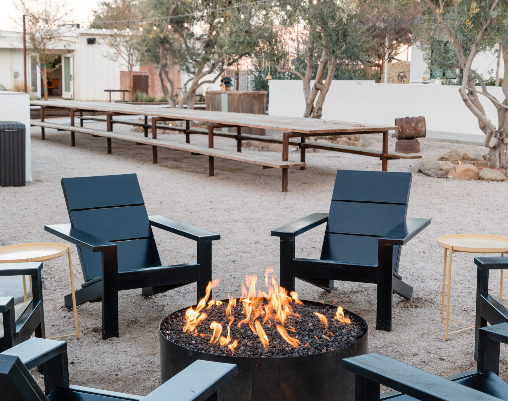 Photo of a fire pit with black wooden chairs on the ground at Cuyama Buckhorn in New Cuyama, California.