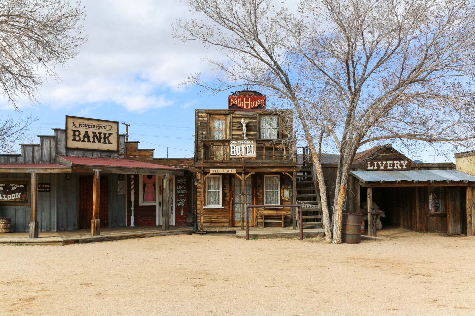 Three Western themed buildings labeled Bank, Bath House, and Livery, on Mane Street in Pioneertown, California.